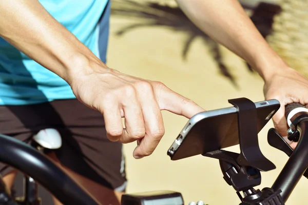 Young man using a smartphone riding a bicycle — Stock Photo, Image