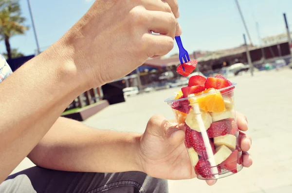 Junger Mann isst Obstsalat im Freien — Stockfoto