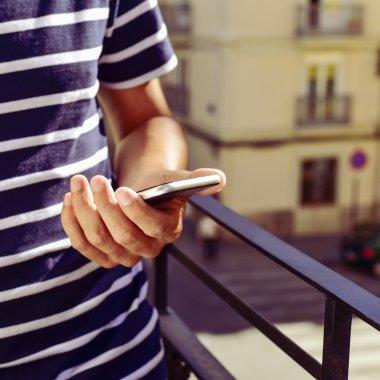 Balkonda onun akıllı telefon kullanan genç adam