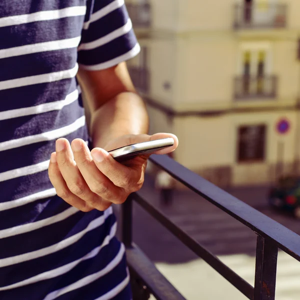 Junger Mann benutzt sein Smartphone auf dem Balkon — Stockfoto