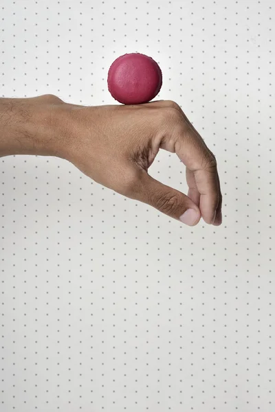 Macaron vermelho na mão de um homem — Fotografia de Stock