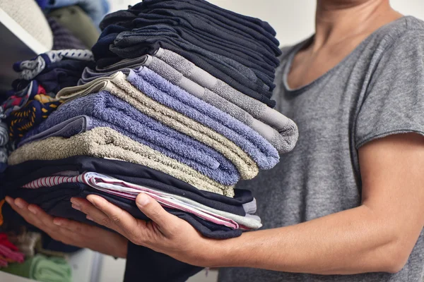 Young man with a pile of folded clothes — Stock Photo, Image