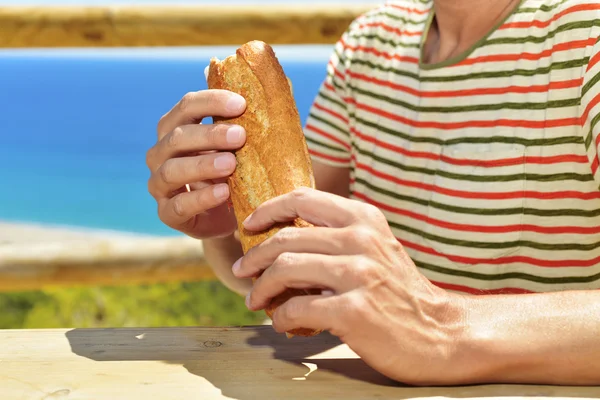 Young man eating a sandwich outdoors — Stock Photo, Image