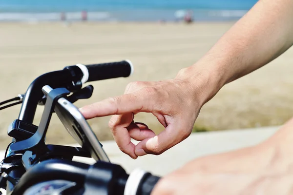 Jovem usando um smartphone montando uma bicicleta — Fotografia de Stock