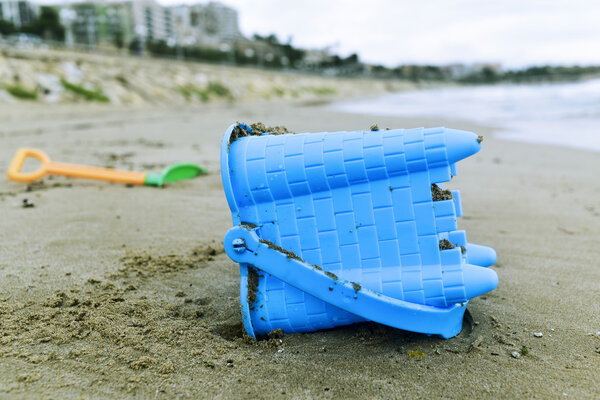 брошенное ведро для игрушек на пляже
