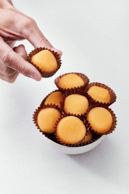 Santa Teresa ya da İspanya 'nın tipik bir örneği olan Yemas de Avila' yı beyaz bir masada ya da tezgahta duran bir kaseden seçen bir adamın yakın çekimi.