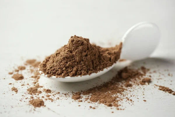 Closeup Pile Carob Powder White Ceramic Spoon Placed White Table — Stock Photo, Image