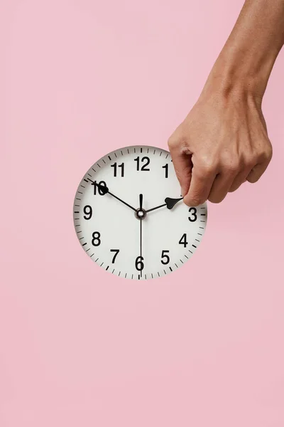 夏の初めにピンクの背景に時計を前後にセットした若い白人男性の手の閉鎖 — ストック写真