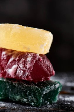 Farklı renklerde boyanmış balkabağı parçalarına yakın plan, İspanyol şekerlemesi genellikle Noel 'de, koyu gri bir arka planda, kırsal gri ahşap bir yüzey üzerinde yenir.