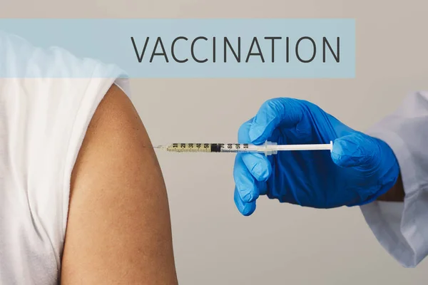 白衣を着て手術用手袋をして白人青年をワクチン接種し文字の予防接種を受け — ストック写真