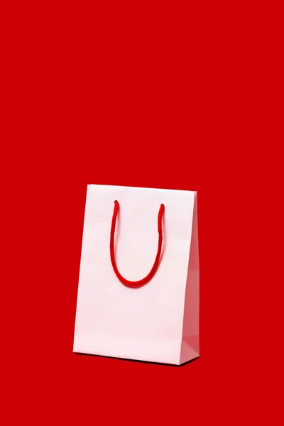 Kırmızı Arka Planda Kırmızı Saplı Beyaz Kağıt Bir Alışveriş Torbası — Stok fotoğraf