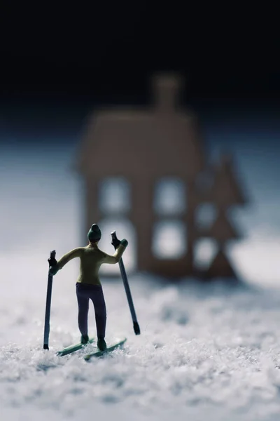 Zbliżenie Miniaturowej Narciarki Jeżdżącej Nartach Śnieżnym Krajobrazie Sylwetka Domu Tle — Zdjęcie stockowe