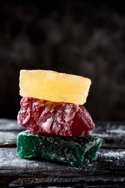 Farklı renklerde boyanmış balkabağı parçalarına yakın plan, İspanyol şekerlemesi genellikle Noel 'de, koyu gri bir arka planda, kırsal gri ahşap bir yüzey üzerinde yenir.