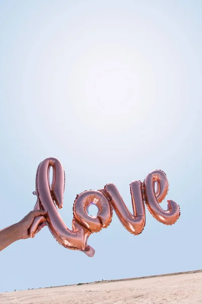 Elinde Mavi Gökyüzüne Karşı Aşk Sözcüğü Şeklinde Bir Balon Tutan — Stok fotoğraf