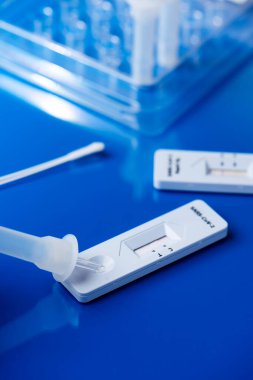 Örneğin mavi bir masada, nazofaringeal bir bezin yanına kovid 19 'un hızlı antijen test cihazına yerleştirilmesinin yakın çekimi.