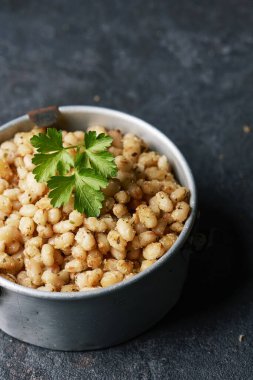 Kayrak taşı yüzeyinde içi kızarmış beyaz fasulye dolu eski bir metal beslenme çantasına yakın çekim.
