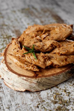 Ahşap bir tepside sunulan ve ahşap bir masaya yerleştirilmiş baharatlı sahte tavuk eti şeritlerinin yakın plan çekimi.