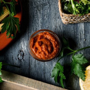 Bu versiyonda badem ve güneşte kurutulmuş domatesle yapılan tipik İspanyol sobrasadasının vejetaryen versiyonu gri bir ahşap masanın üzerinde duran cam kasenin yüksek açılı görüntüsü.