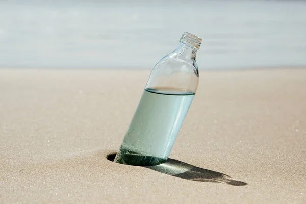 Una Bottiglia Acqua Riutilizzabile Vetro Sulla Sabbia Bagnata Della Riva — Foto Stock