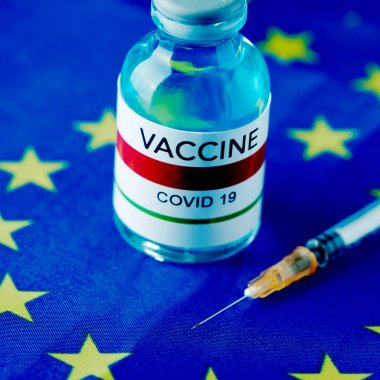 Avrupa Birliği bayrağında simüle edilmiş covid-19 aşısı ve şırınganın yakın çekimi