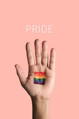 the open hand of a man with a rainbow flag painted in his palm, and the text pride against a pale pink background clipart