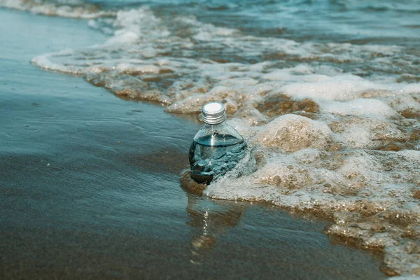 Скляна Багаторазова Пляшка Води Узбережжі Самотнього Пляжу Поруч Пінистою Хвилею — стокове фото