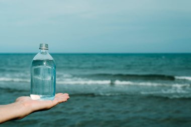 Kafkas 'lı genç bir adamın elinde bir bardak dolusu su var, okyanusun önünde.