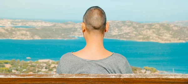 イタリアのサルデーニャ島の北海岸にあるパラオのベンチに座っている若い男の閉鎖は 地中海とラ マダレナ諸島をウェブバナーとして使用するパノラマ形式で観察しています — ストック写真