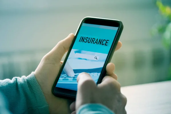 Young Caucasian Man Sitting Table Searches Insurance Online His Smartphone — Stock Photo, Image