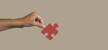 Kafkas 'lı genç bir adamın elinde kırmızı bir yapboz parçası var, soluk kahverengi bir zemin üzerinde, panoramik bir formatta web pankartı ya da başlık olarak kullanılacak