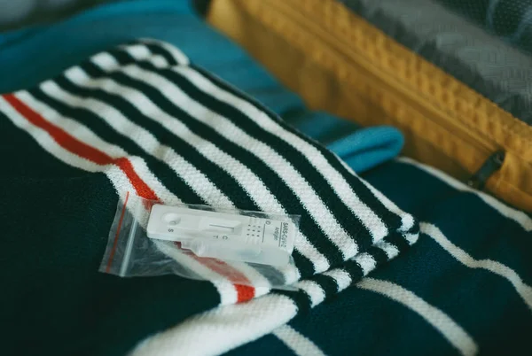 Bir Bavulun Içinde Farklı Kıyafetlerle Paketlenmiş Bir Covid Antijen Test — Stok fotoğraf