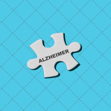 Mavi arkaplanda Alzheimer yazan beyaz bir bulmaca parçası.