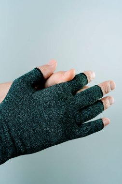 Kafkasyalı bir adamın beyaz bir arka planda sıkıştırma eldiveni giydiği ya da çıkardığı yakın plan.