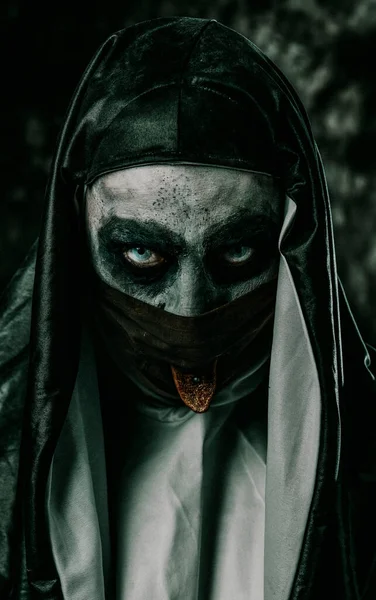 一个可怕的邪恶修女 有着典型的黑白相间的习惯 把她那被刺穿的舌头伸进了黑脸面具的孔里 — 图库照片
