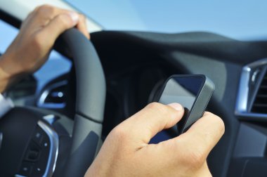 Araba sürerken bir akıllı telefon kullanan adam