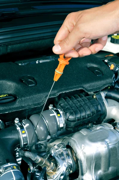 Joven que mide el nivel de aceite de motor con una varilla de inmersión — Foto de Stock