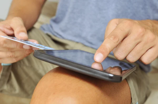 Молодой человек делает покупки онлайн через планшетный компьютер — стоковое фото