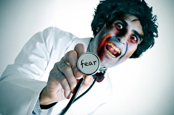Um médico zumbi com a palavra medo escrito em seu estetoscópio — Fotografia de Stock