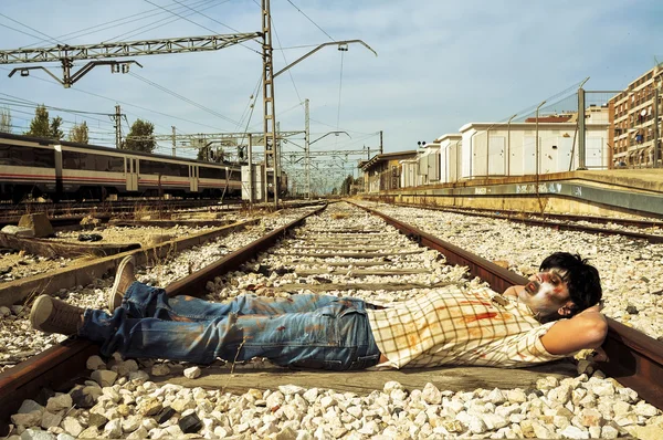 Zombie effrayant faire une sieste sur les voies ferrées abandonnées — Photo