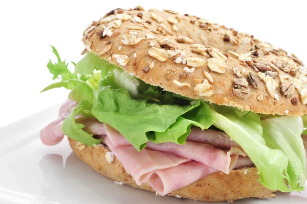 Brown bagel filled with ham and lettuce mix — Stock Photo, Image