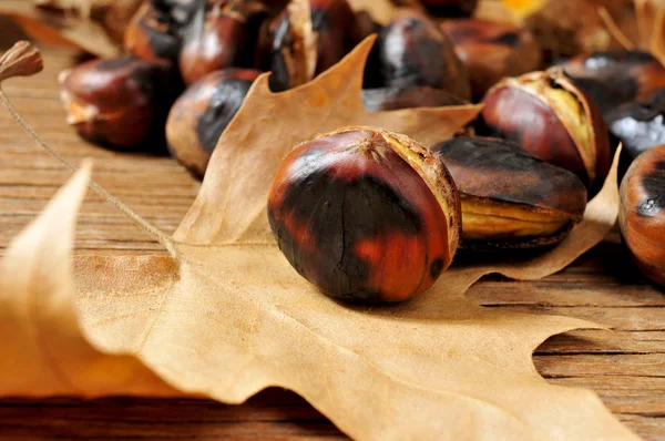 Roasted chestnuts and autumn leaves — Stock Photo, Image