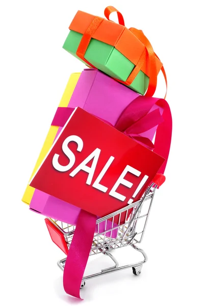 Gåvor och en skylt med ordet försäljning i en shoppingvagn — Stockfoto