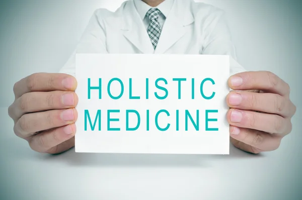 Doctor with a signboard with the text holistic medicine — Stock Photo, Image