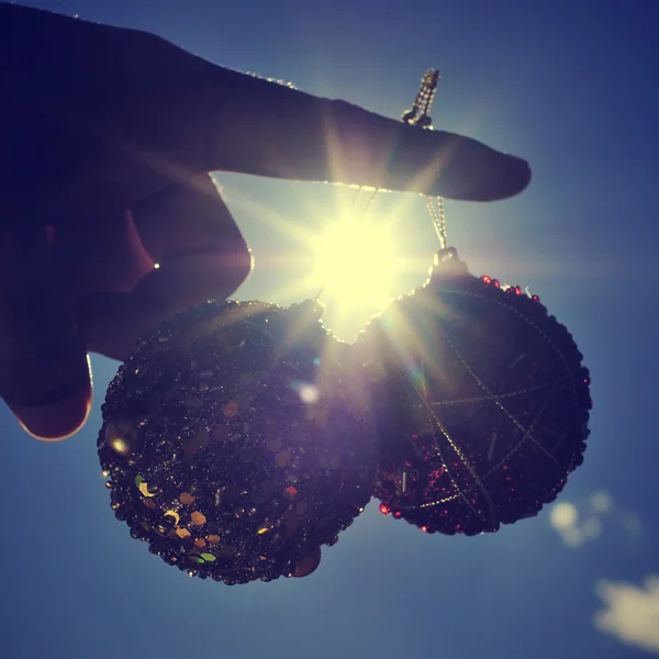 Bolas de Navidad en el dedo índice con un rayo de sol y retroiluminado, con — Foto de Stock