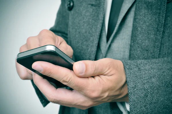 Businessman in coat using a smartphone — Stock Photo, Image