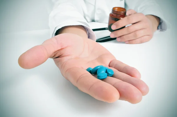 Médico en una sala de consulta con un montón de pastillas — Foto de Stock