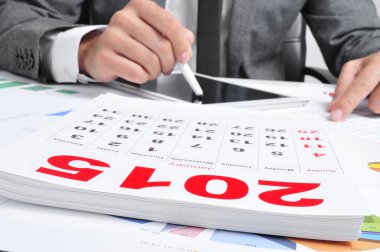 bir tablet ve 2015 takvim kullanarak takım elbiseli adam