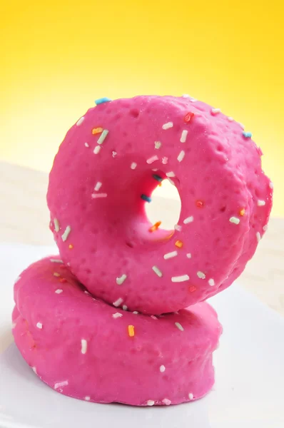 Donuts coated with a pink frosting and sprinkles of different co — Stock Photo, Image