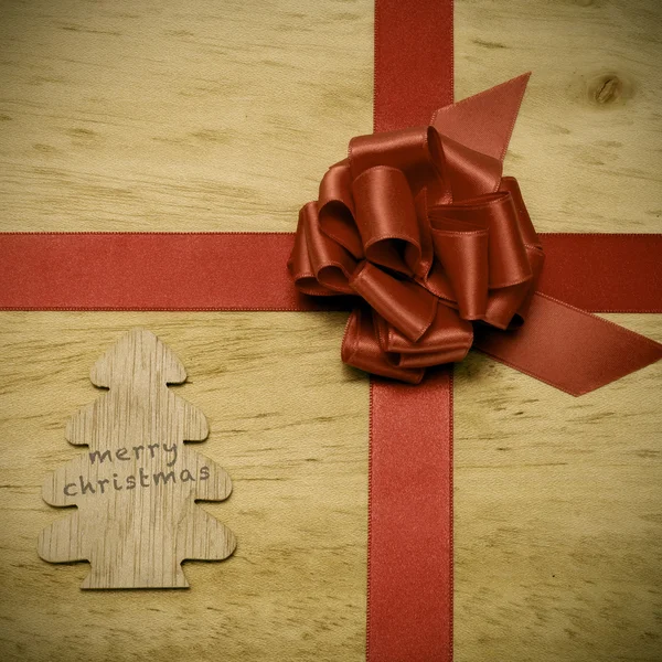 Feliz Navidad escrito en un árbol de madera y un lazo de cinta roja —  Fotos de Stock