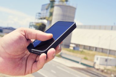 bir endüstri parkında bir akıllı telefon kullanan adam
